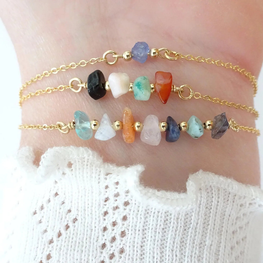 Two gold anklets with colorful beads on a person's ankle against a white background.