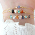 Two gold anklets with colorful beads on a person's ankle against a white background.